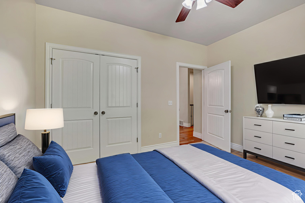 Bedroom featuring a closet, wood finished floors, a ceiling fan, and baseboards
