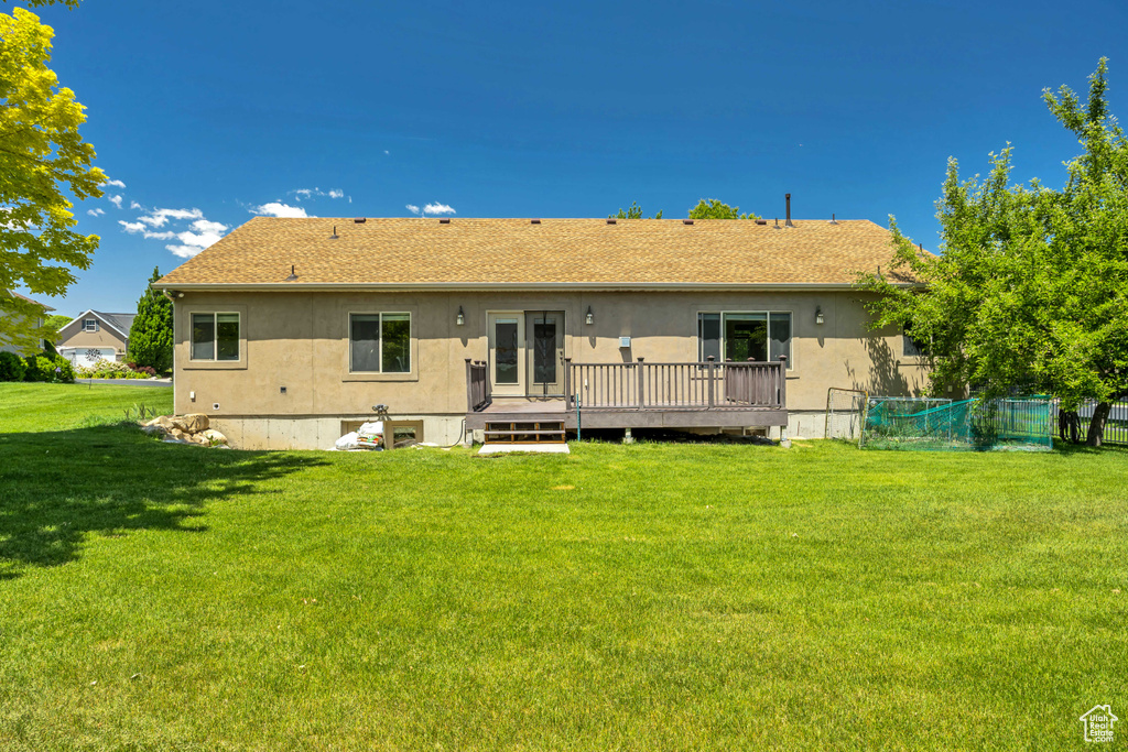 Rear view of house with a deck, stucco siding, and roof with shingles