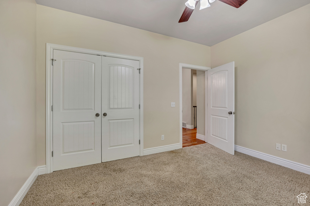 Unfurnished bedroom featuring carpet flooring, a closet, baseboards, and ceiling fan