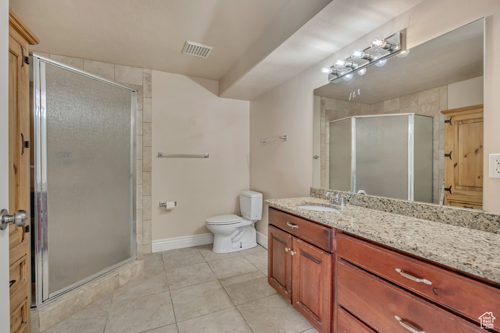Full bath with vanity, a stall shower, toilet, baseboards, and tile patterned floors