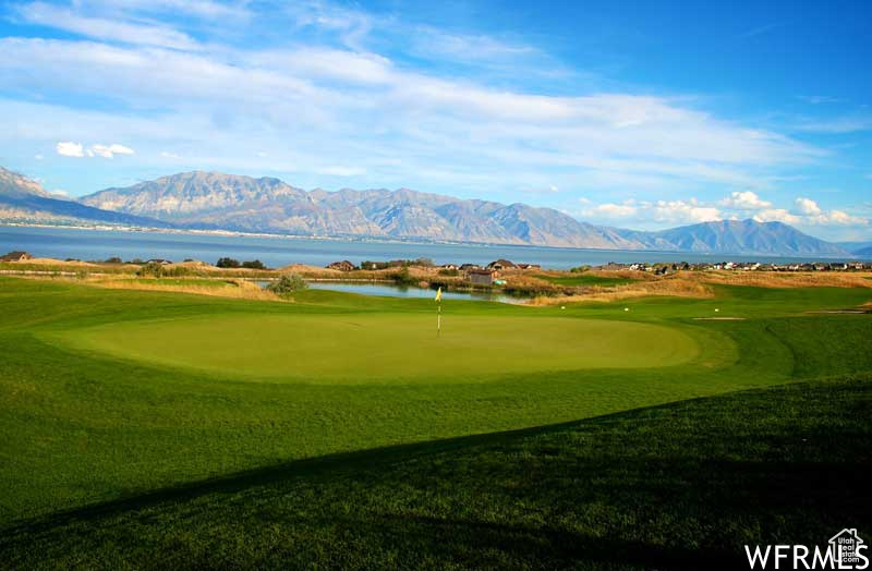 View of property\'s community with a putting green, a water and mountain view, and view of golf course
