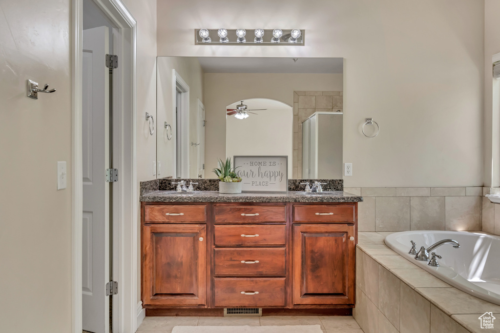 Bathroom featuring a stall shower, a ceiling fan, a bath, double vanity, and tile patterned floors