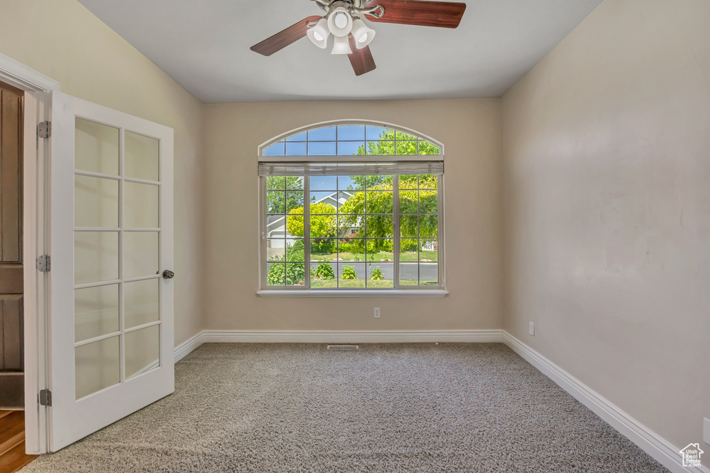 Carpeted spare room with baseboards and a ceiling fan