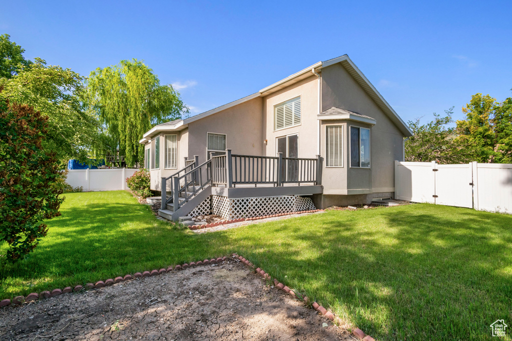 Back of house featuring a gate, a deck, and stucco siding