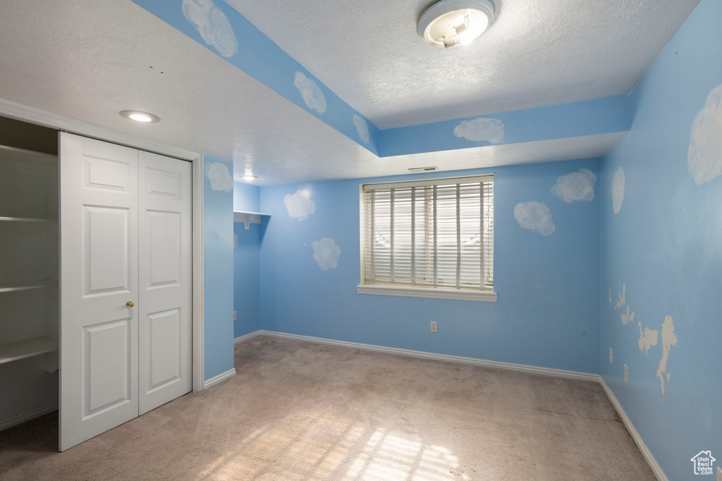 Unfurnished bedroom featuring carpet floors, a textured ceiling, a closet, and baseboards
