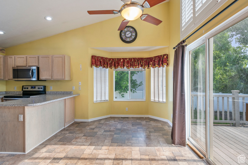 Kitchen with stainless steel appliances, stone tile floors, plenty of natural light, baseboards, and high vaulted ceiling