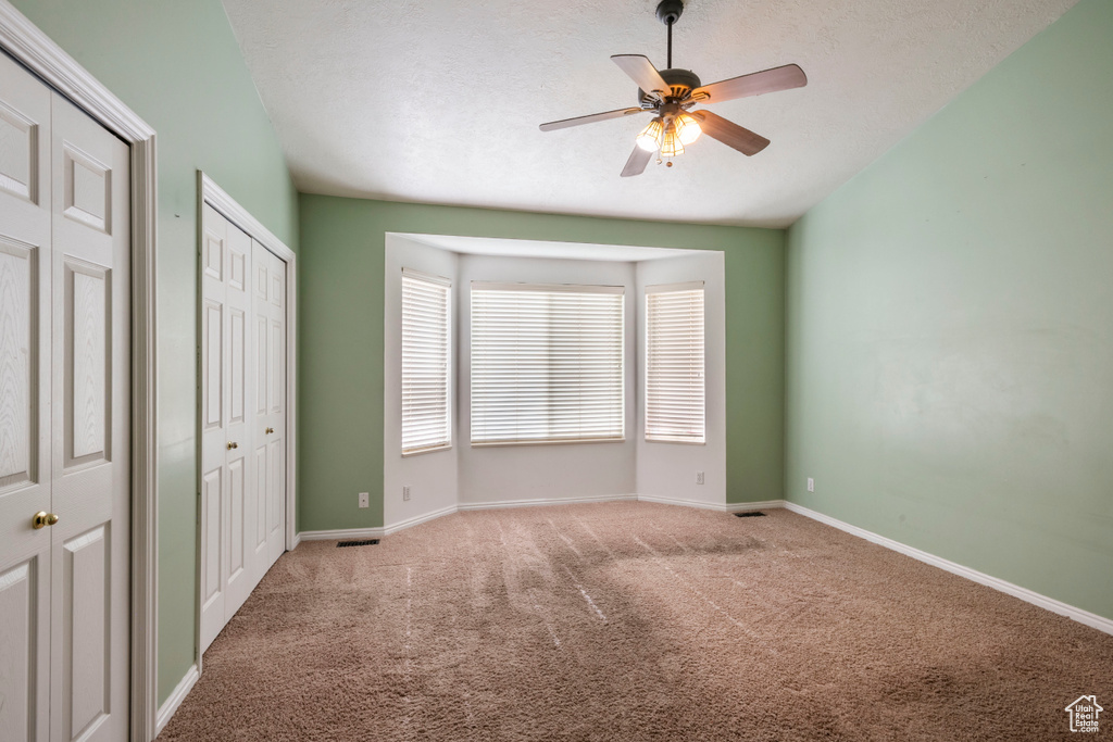 Unfurnished bedroom featuring carpet, multiple closets, baseboards, and a ceiling fan