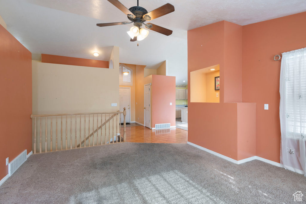Empty room with carpet floors, a ceiling fan, baseboards, and vaulted ceiling
