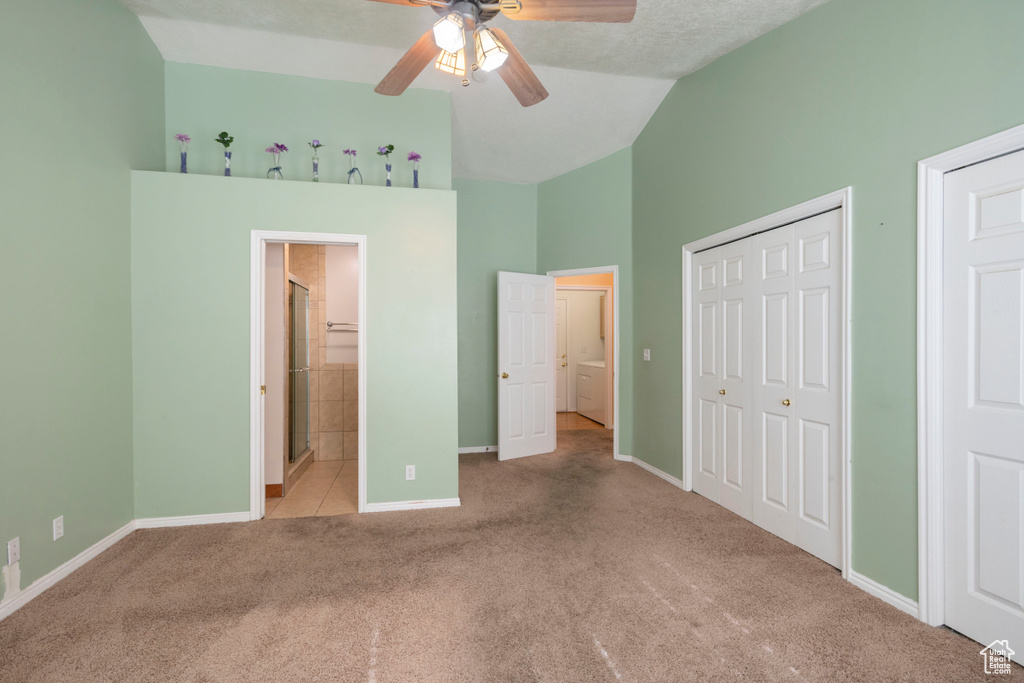 Unfurnished bedroom featuring carpet, high vaulted ceiling, baseboards, a ceiling fan, and ensuite bath