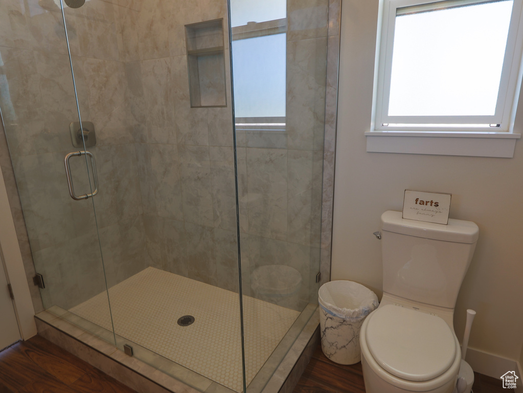 Bathroom with toilet, a shower stall, and wood finished floors