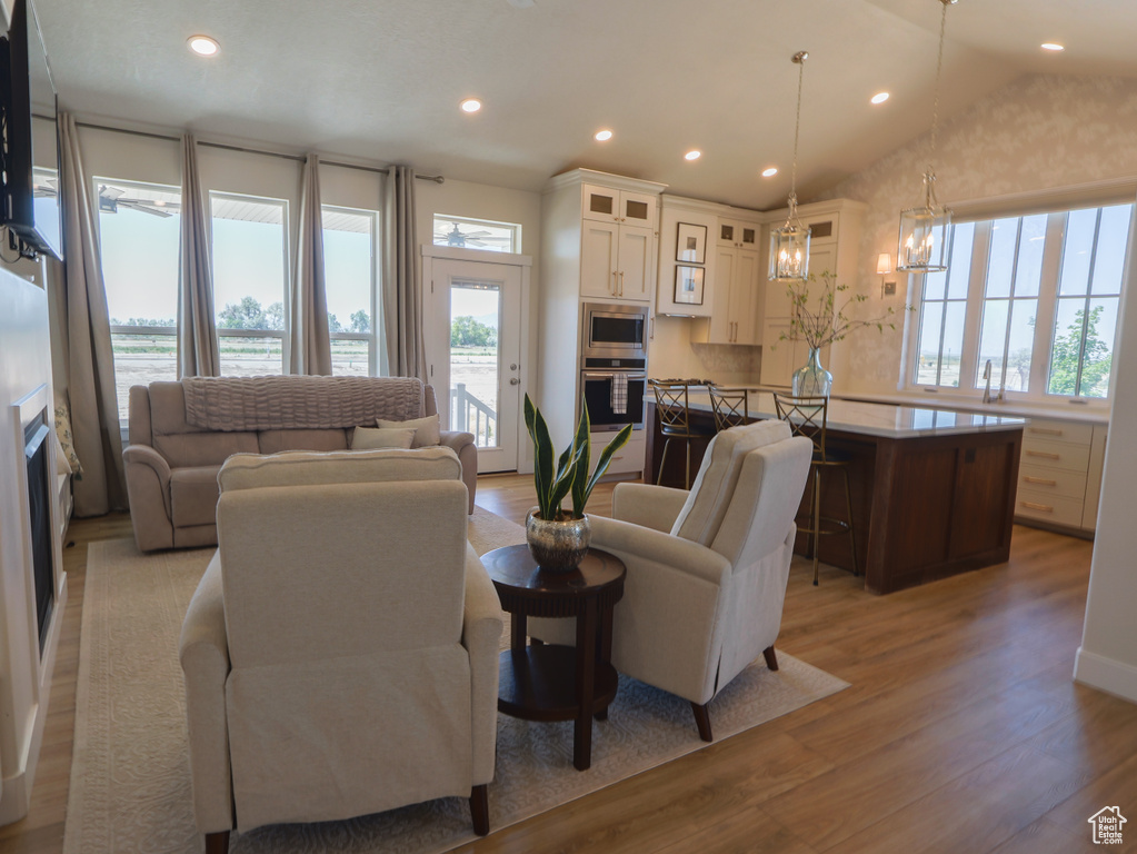 Living area featuring plenty of natural light, light wood-type flooring, a chandelier, recessed lighting, and vaulted ceiling
