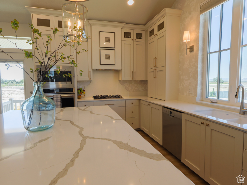 Kitchen with stainless steel appliances, a sink, glass insert cabinets, white cabinets, and recessed lighting