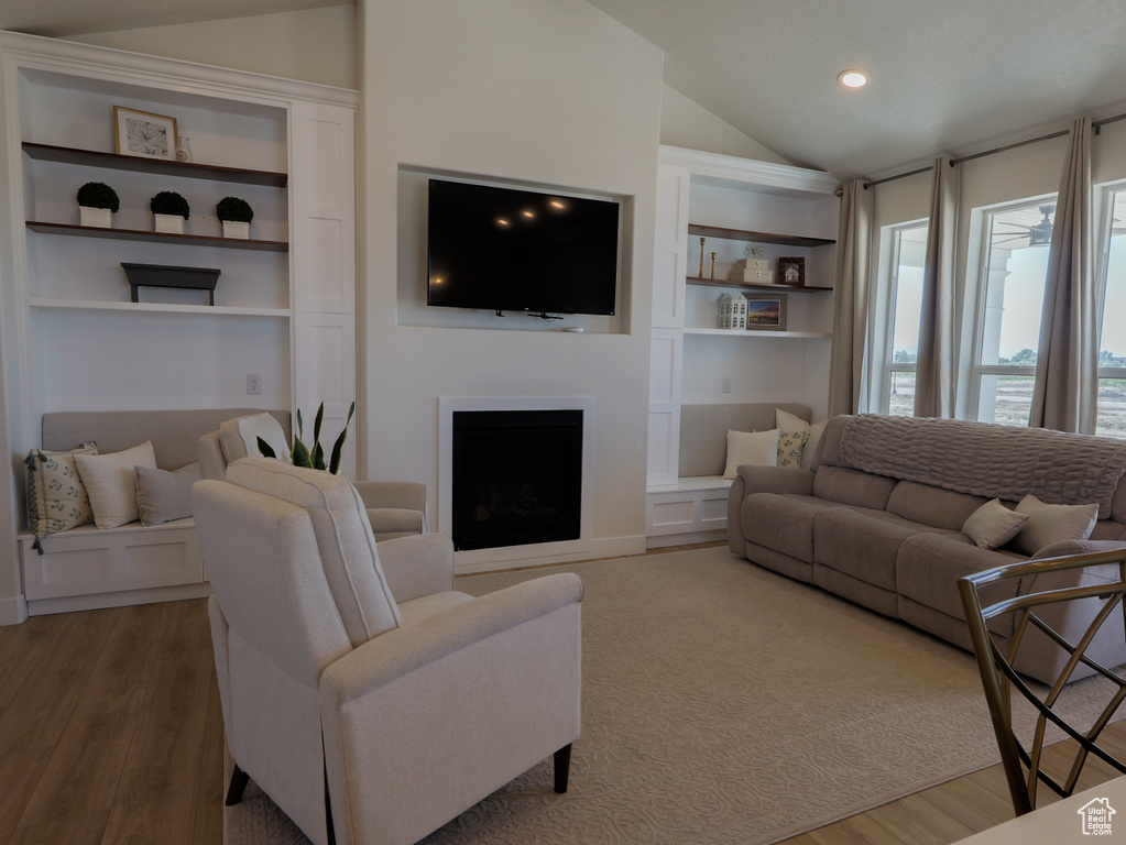 Living area featuring lofted ceiling, built in features, wood finished floors, a fireplace, and recessed lighting