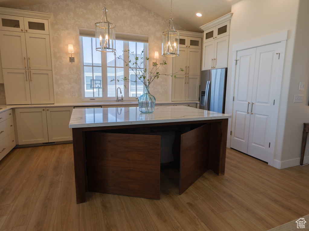 Kitchen featuring stainless steel fridge with ice dispenser, wood finished floors, a chandelier, a sink, and lofted ceiling