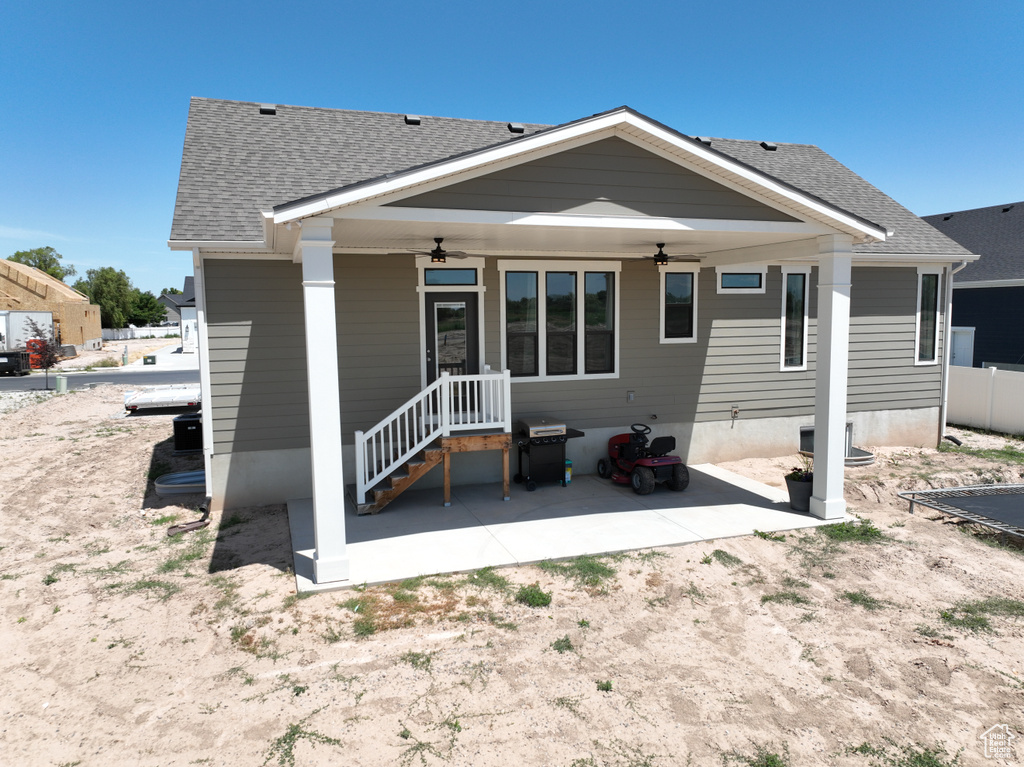Rear view of property featuring a ceiling fan, a shingled roof, and a patio area