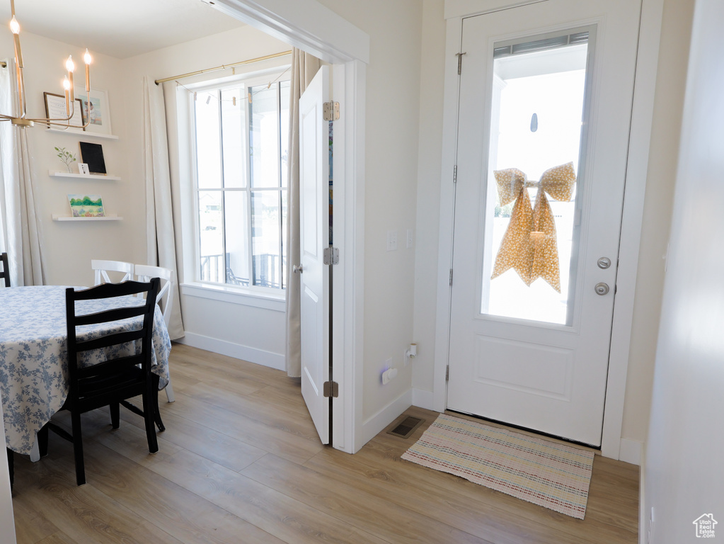 Entryway with a chandelier, baseboards, and light wood-style floors