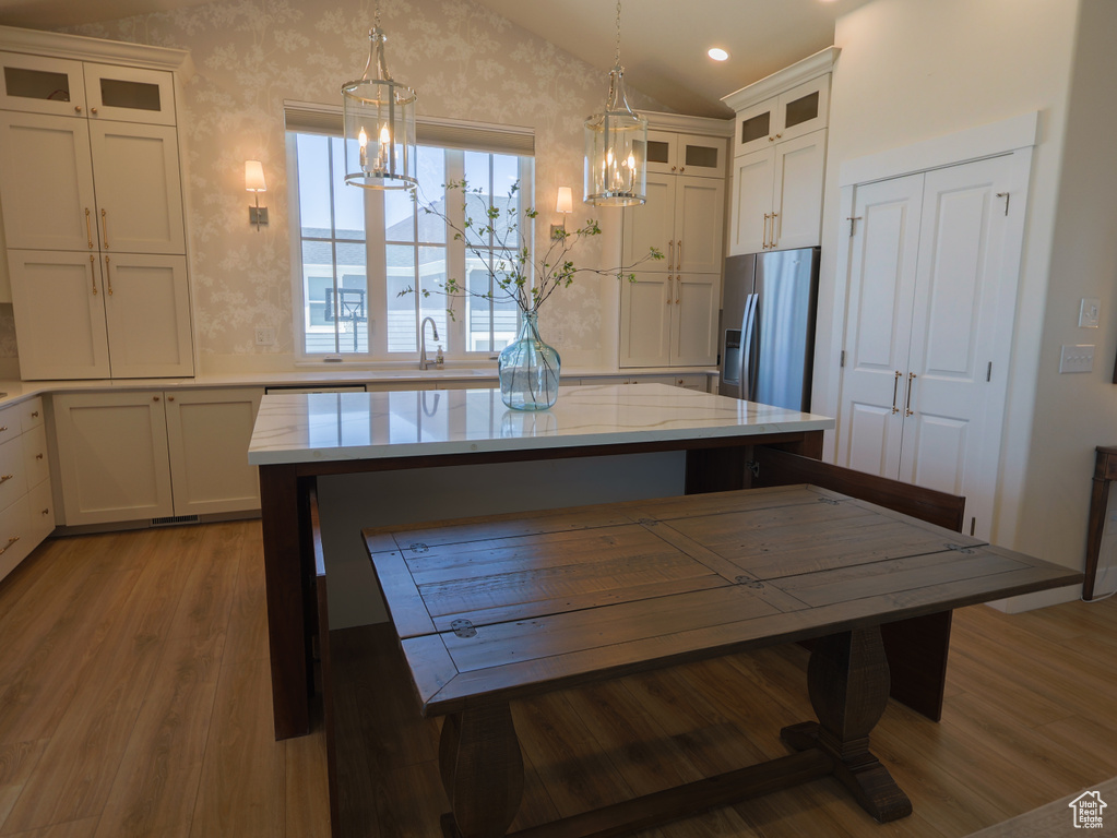 Kitchen featuring stainless steel fridge with ice dispenser, a chandelier, lofted ceiling, wood finished floors, and white cabinetry