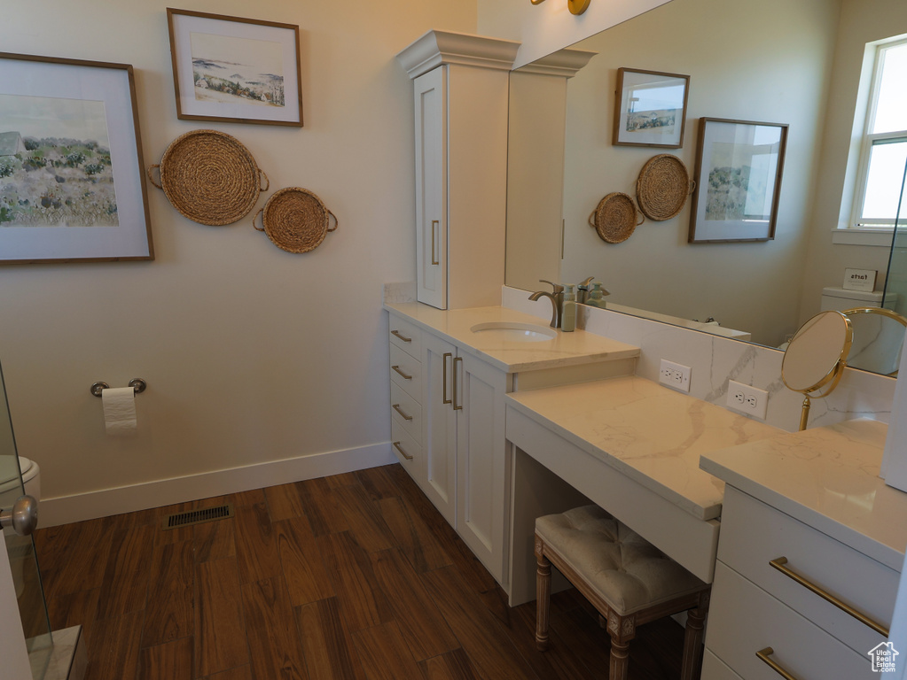 Bathroom featuring toilet, wood finished floors, vanity, and baseboards