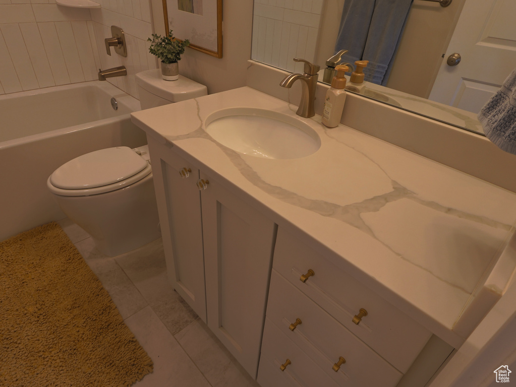 Bathroom with toilet, vanity, tile patterned floors, and  shower combination