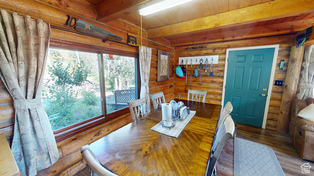 Dining space with log walls, wood ceiling with exposed beams, and wood finished floors