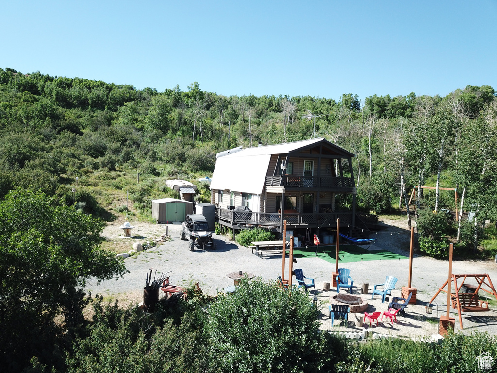 Rear view of house with a fire pit, a forest view, a balcony, and a patio area