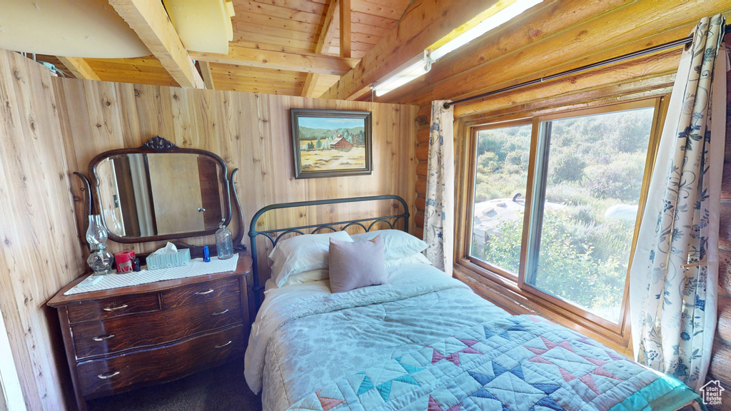 Bedroom with beamed ceiling and wooden walls