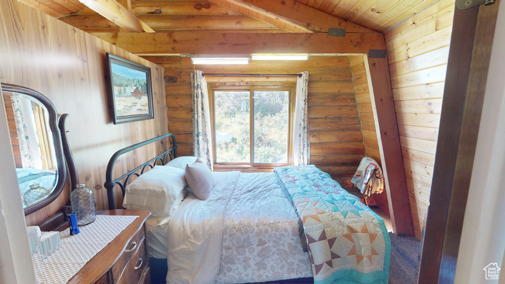 Bedroom with log walls and wood ceiling with exposed beams