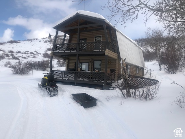 Snow covered rear of property featuring a balcony and log exterior