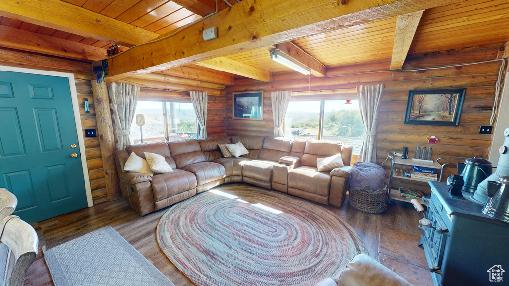 Living area with log walls, wooden ceiling with exposed beams, and wood finished floors