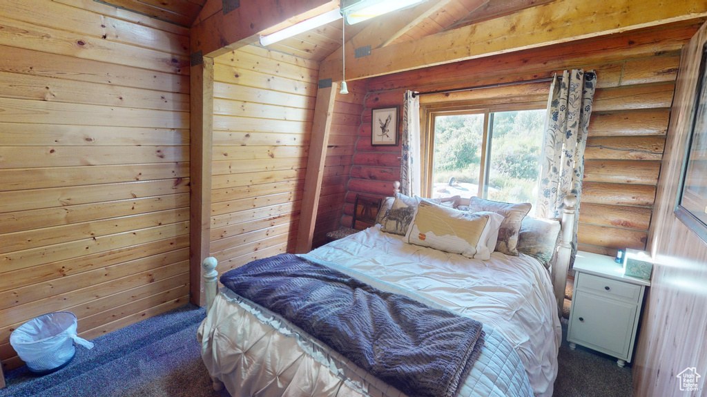 Carpeted bedroom with lofted ceiling, wooden walls, and log walls