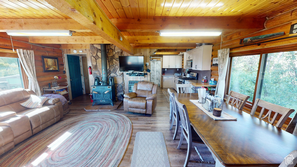 Living room with a wood stove, wood finished floors, and wood ceiling with exposed beams