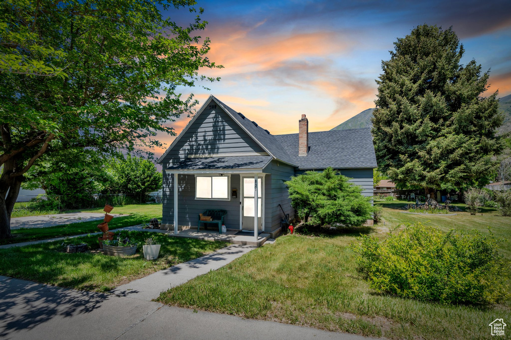 Bungalow with a chimney, a front lawn, and roof with shingles