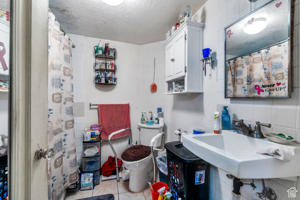 Full bath with toilet, tile patterned floors, a textured ceiling, a sink, and a shower with curtain