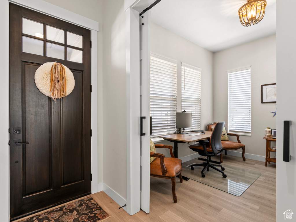 Foyer featuring light wood-style floors, baseboards, and a chandelier