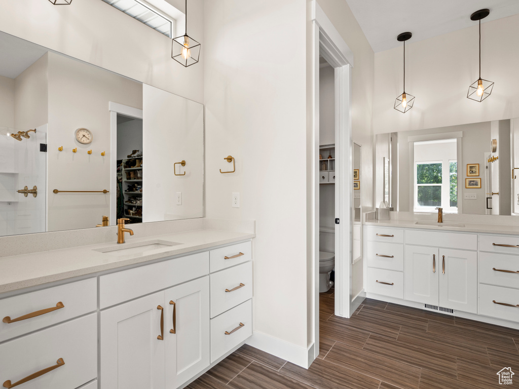 Full bathroom featuring a spacious closet, vanity, wood finish floors, toilet, and baseboards