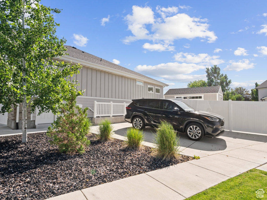 View of side of property featuring board and batten siding, concrete driveway, roof with shingles, and an attached garage