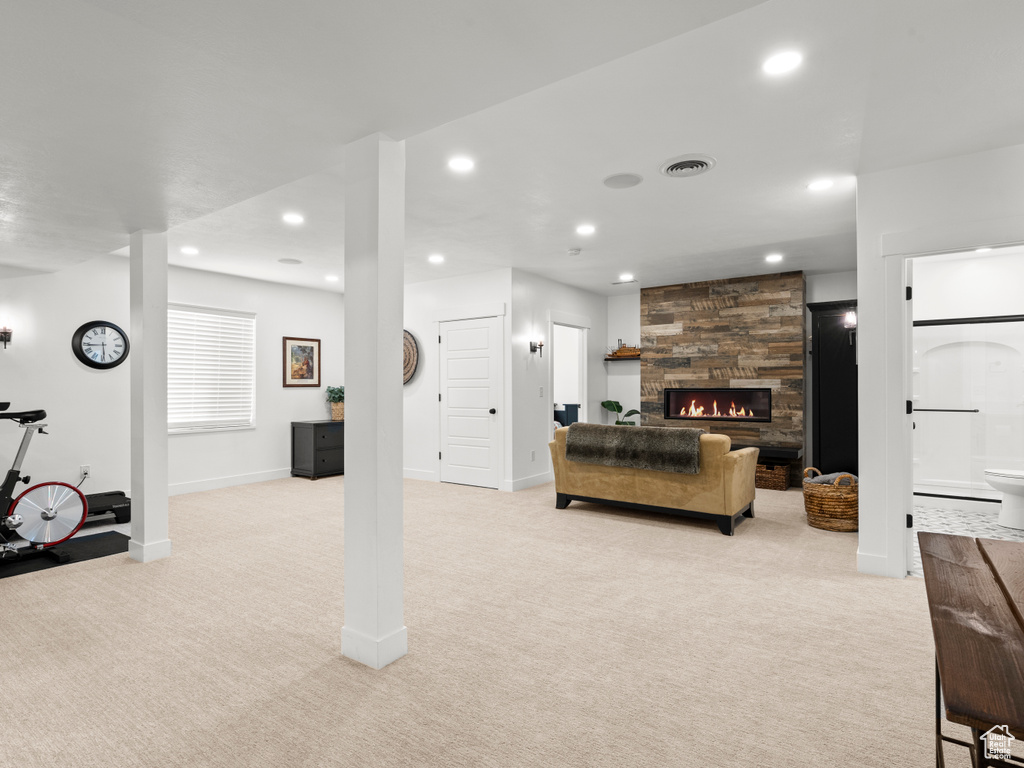 Living area featuring light carpet, recessed lighting, baseboards, and a stone fireplace