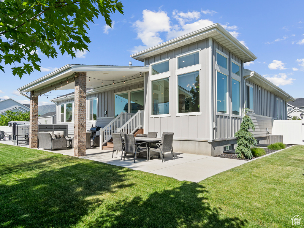 Back of property featuring board and batten siding, a patio area, and an outdoor hangout area