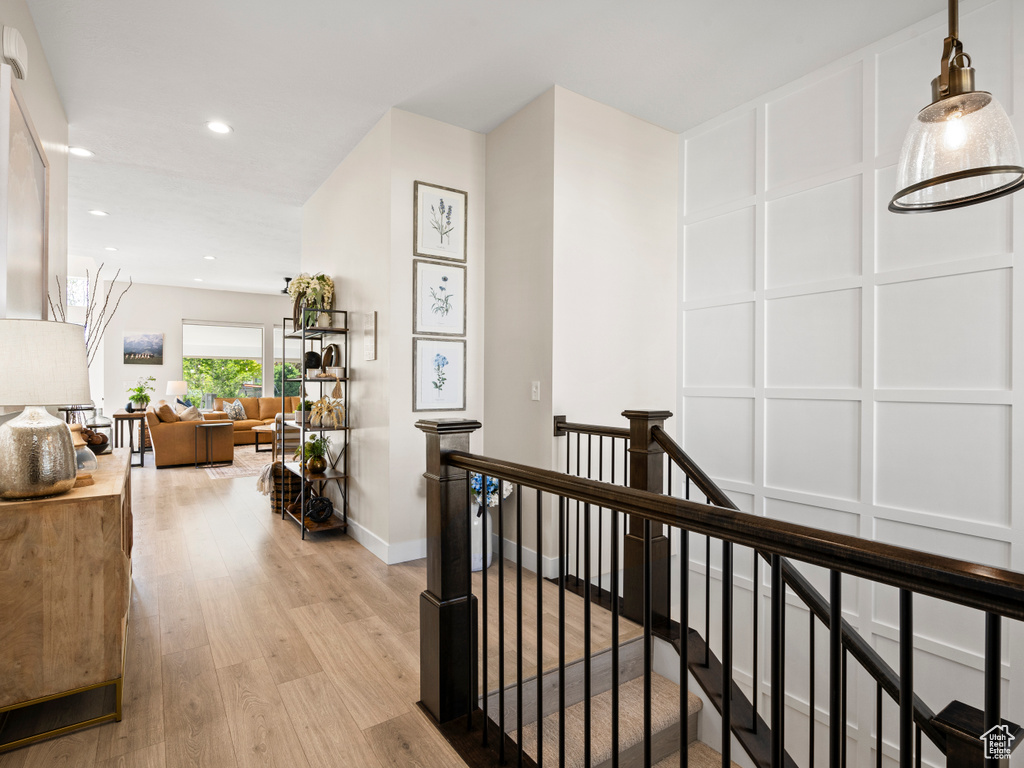 Corridor with an upstairs landing, light wood finished floors, recessed lighting, and baseboards