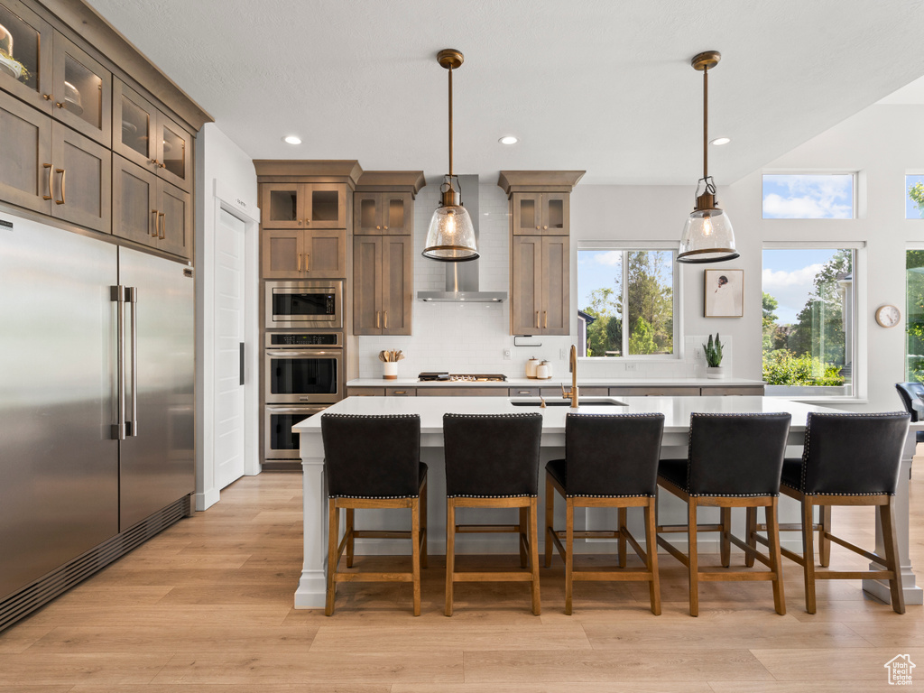 Kitchen featuring built in appliances, a sink, light countertops, decorative backsplash, and recessed lighting