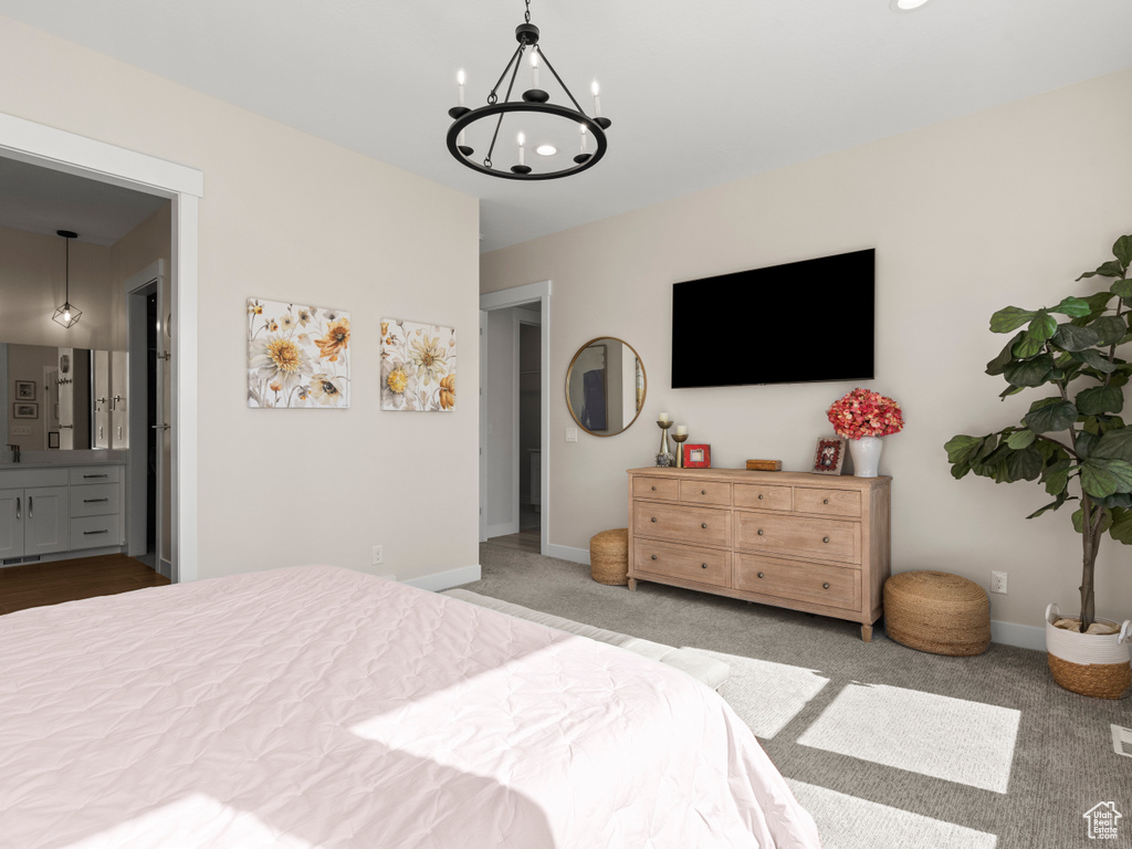 Carpeted bedroom with a chandelier, connected bathroom, and baseboards