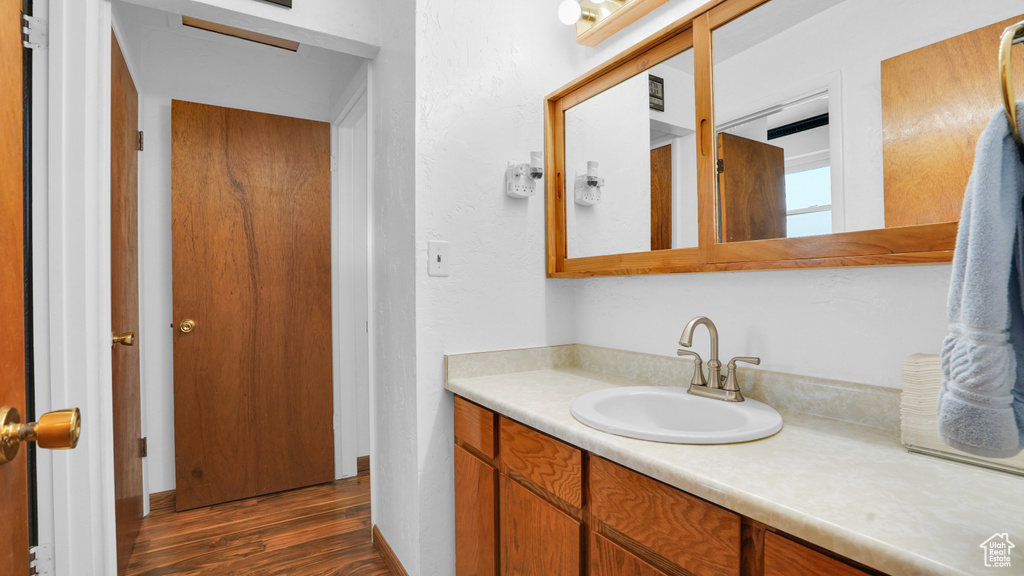 Bathroom featuring wood finished floors, vanity, and baseboards