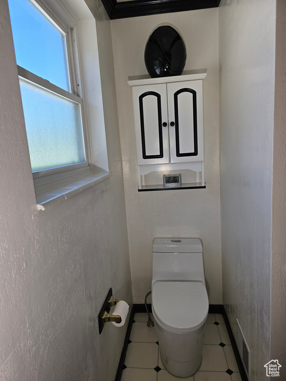 Bathroom featuring toilet, baseboards, and tile patterned floors