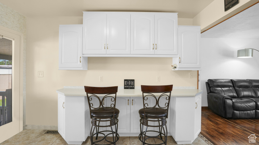 Kitchen featuring white cabinets, a kitchen breakfast bar, and light countertops