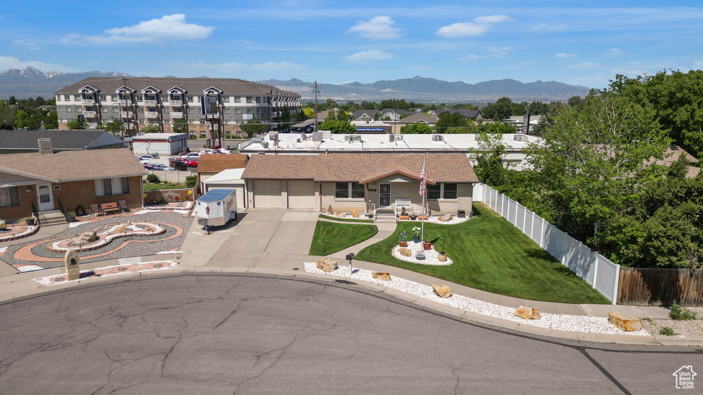 View of front of home with a mountain view, driveway, and a residential view
