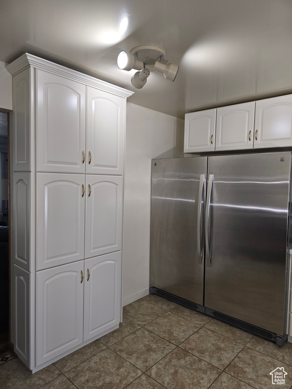 Kitchen with freestanding refrigerator, white cabinetry, and baseboards