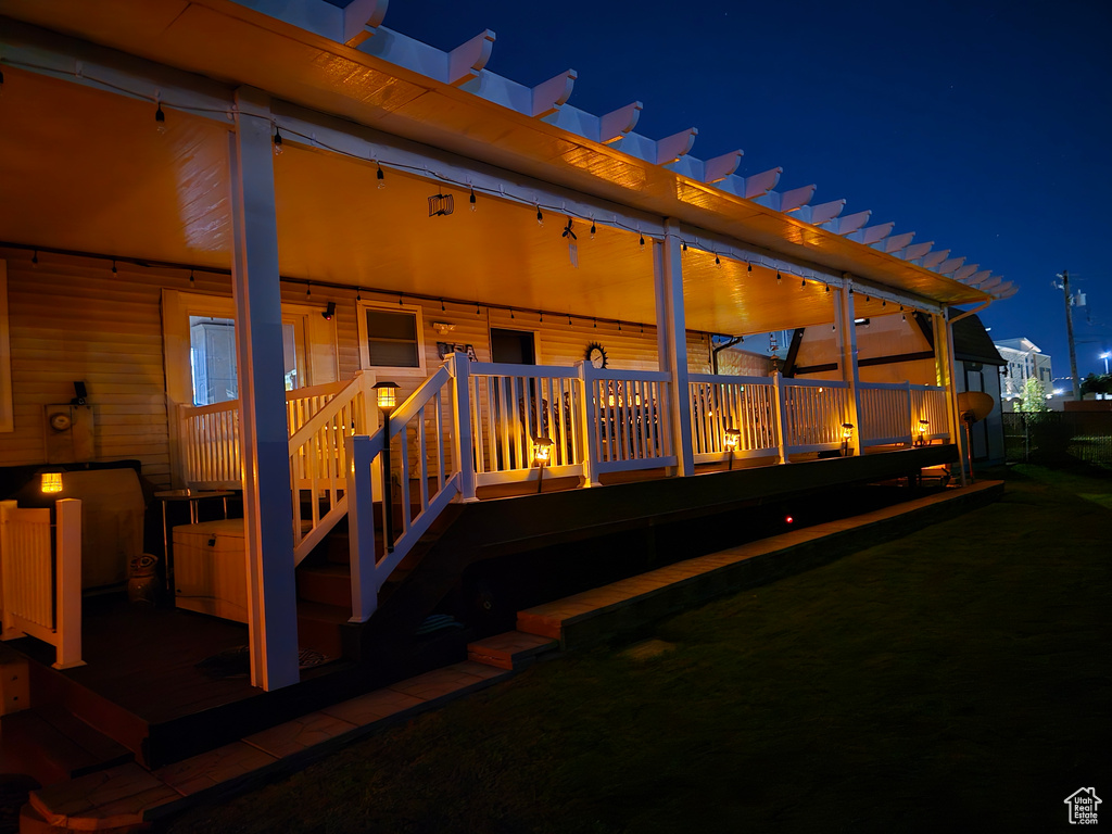 Back of house at twilight featuring a deck and a pergola