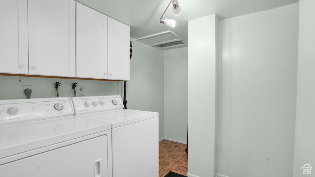 Washroom featuring washing machine and clothes dryer, cabinet space, and attic access