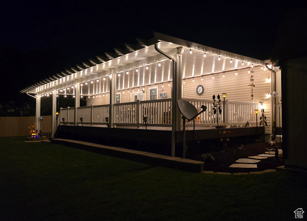 Back of house at night featuring a pergola and a wooden deck