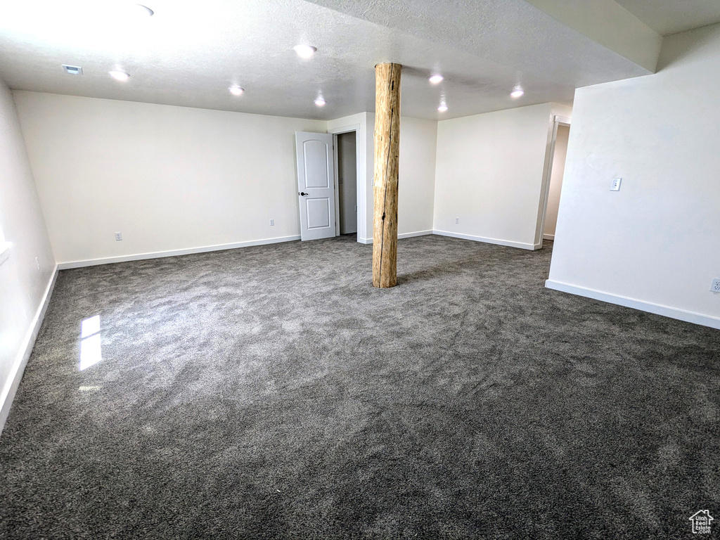 Finished basement with dark colored carpet and baseboards